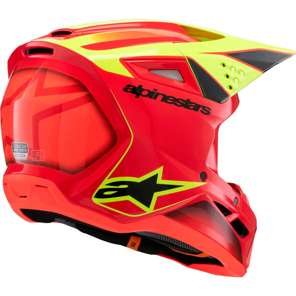 A red and neon yellow Alpinestars full-face motocross helmet with a black visor and interior padding, shown from a three-quarters angle on a white background.