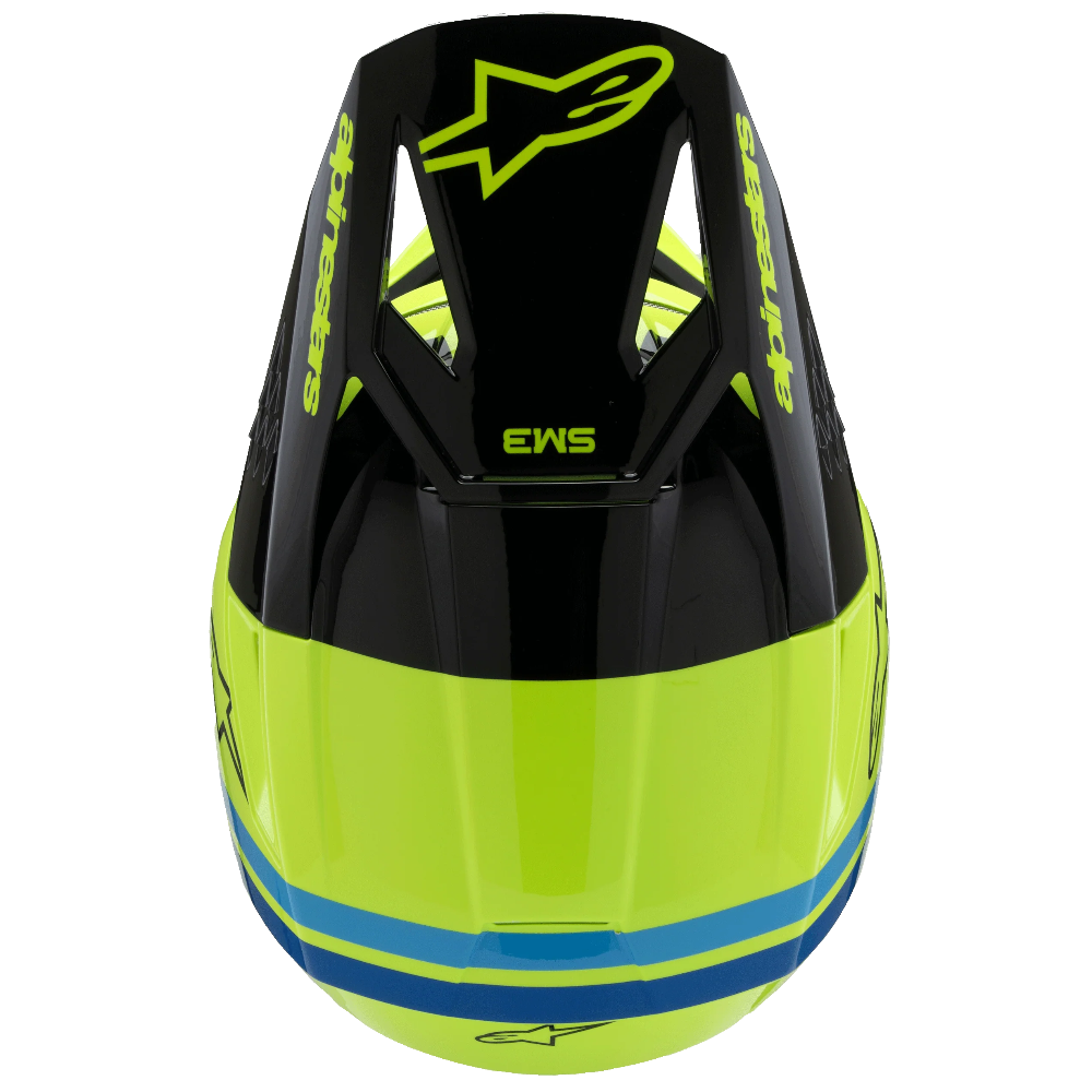 A close-up top view of a motocross helmet in neon yellow-green and black, featuring a blue stripe near the bottom and the Alpinestars logo.