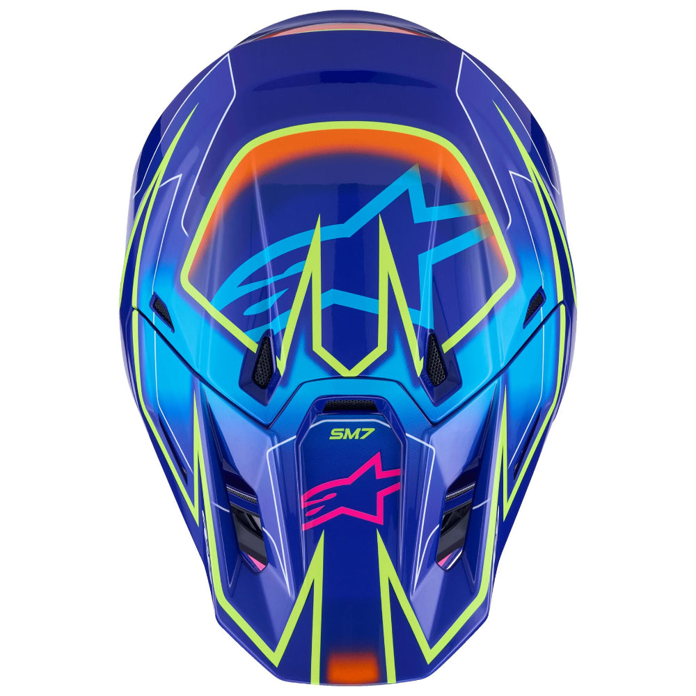 Alpinestars SM7 motocross helmet in a vibrant blue colorway with neon yellow, orange, and pink graphic accents, shown on a solid white background.