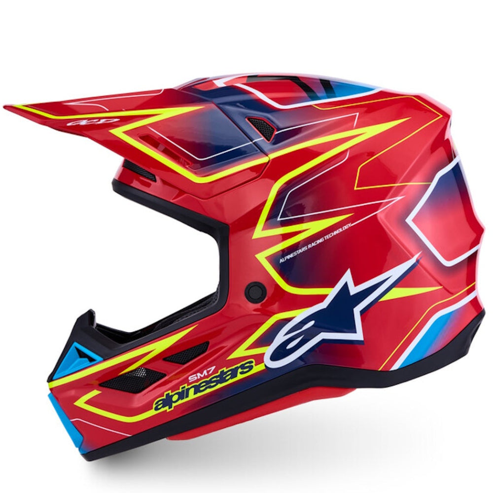 A red Alpinestars full-face motocross helmet with yellow, blue, and black graphic accents, shown from a side profile on a white background.