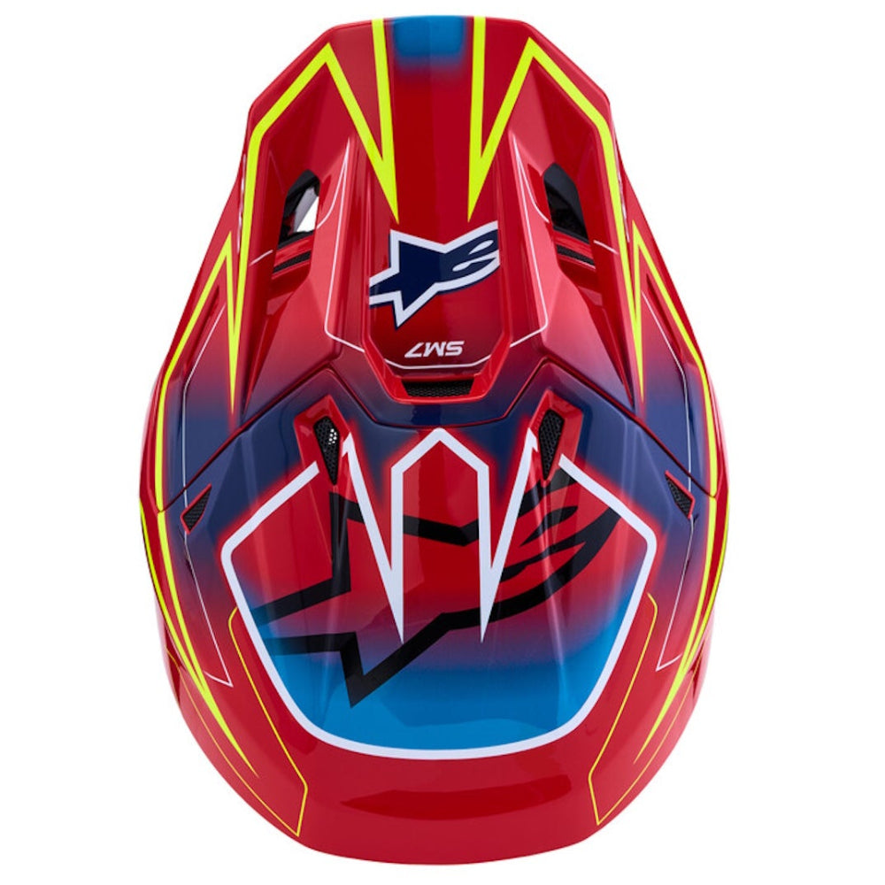 A red Alpinestars full-face motocross helmet with yellow and blue graphic accents, shown from the front on a solid white background.