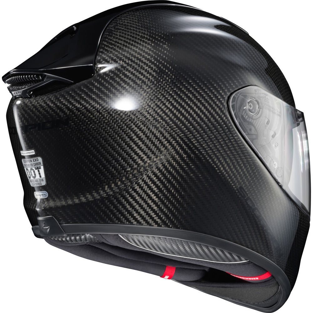 A full-face motorcycle helmet featuring a glossy black carbon fiber weave pattern, a clear visor, and a dark interior with a small red accent visible at the chin.