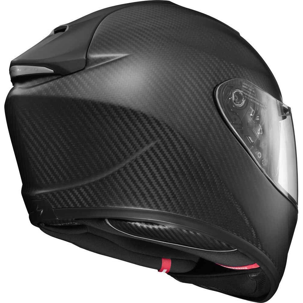 A full-face motorcycle helmet with a black carbon fiber weave pattern, featuring a clear visor and a small red accent at the bottom.