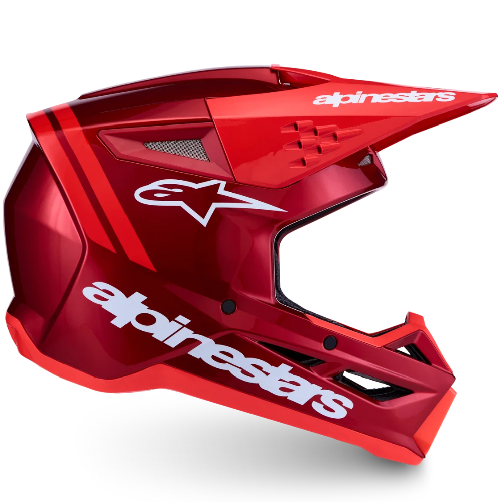 A red Alpinestars full-face motocross helmet with white branding and graphic decals, shown from a three-quarters angle on a white background.