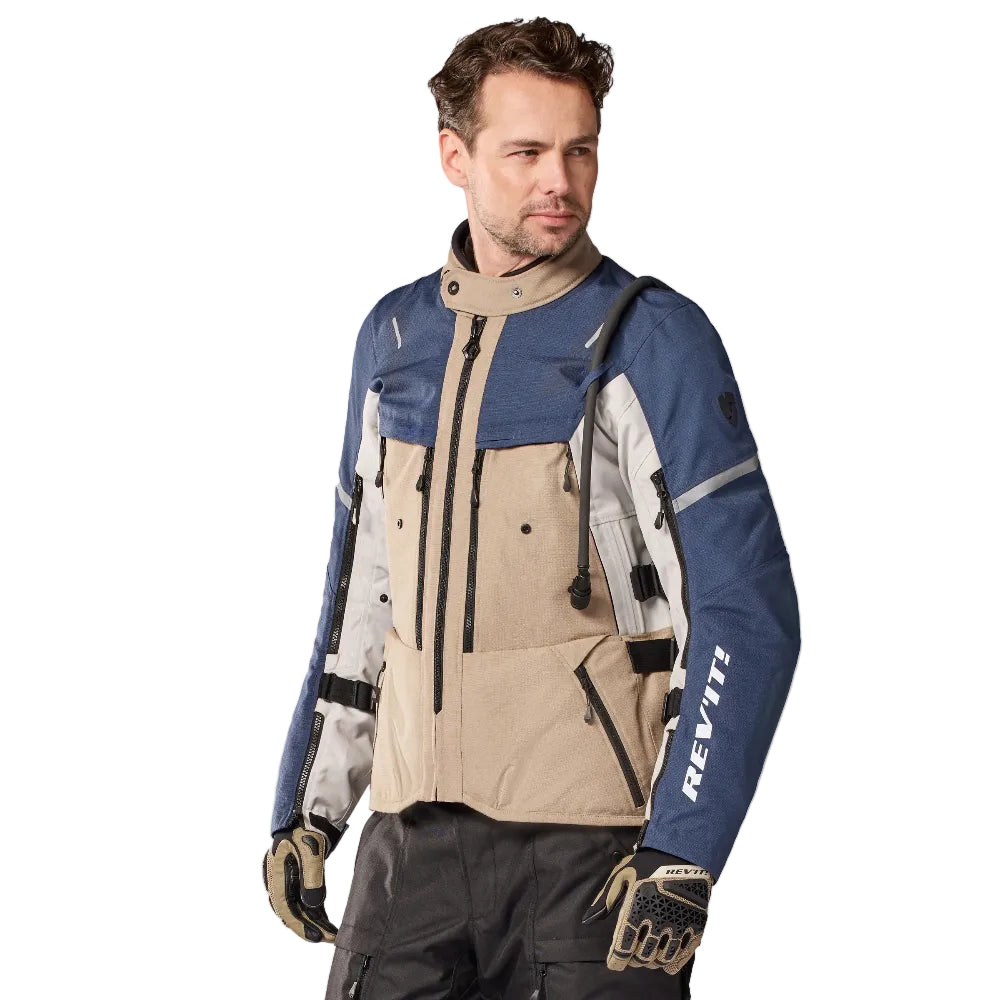 Man wearing a blue and beige jacket with 'Rev'it' branding on a white background
