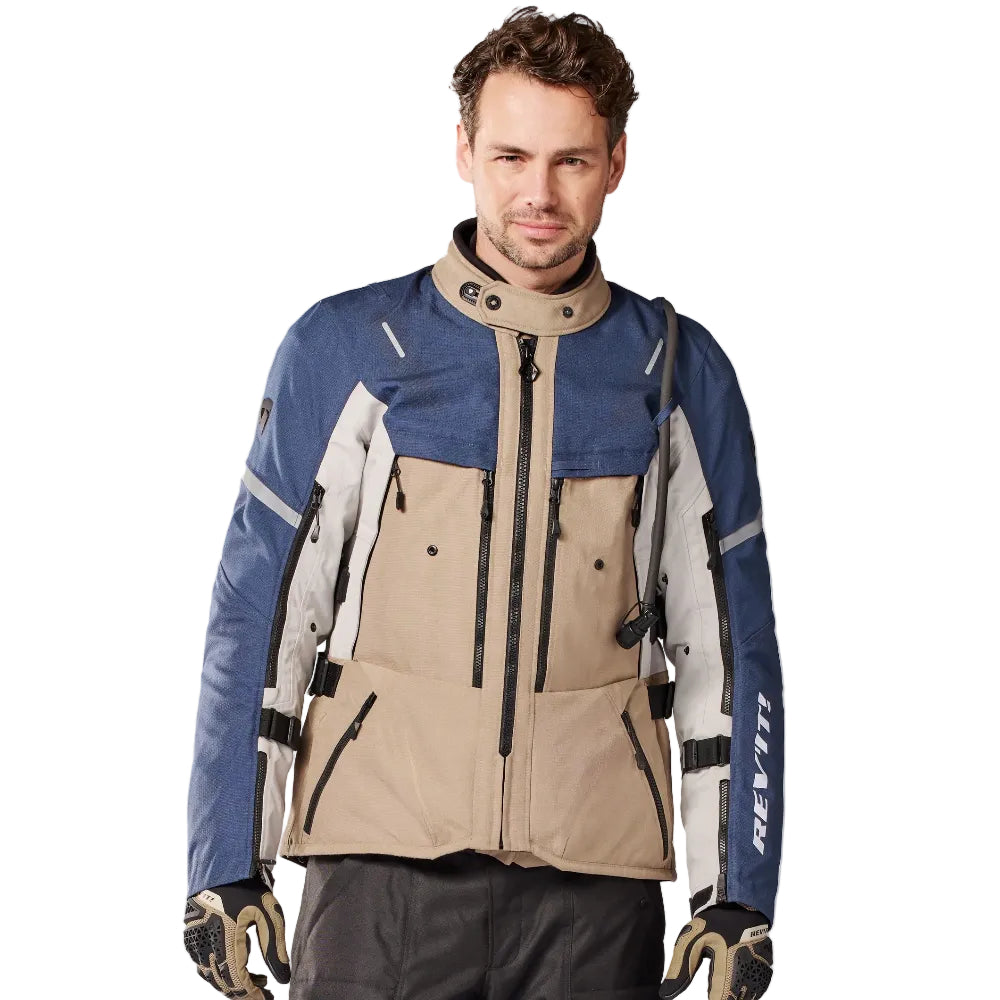 Man wearing a blue and beige jacket with black pants on a white background