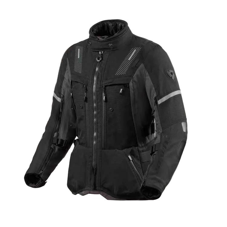 A black technical motorcycle jacket with multiple zippered pockets, reflective gray stripes, and textured ventilation panels, shown on a light beige background.