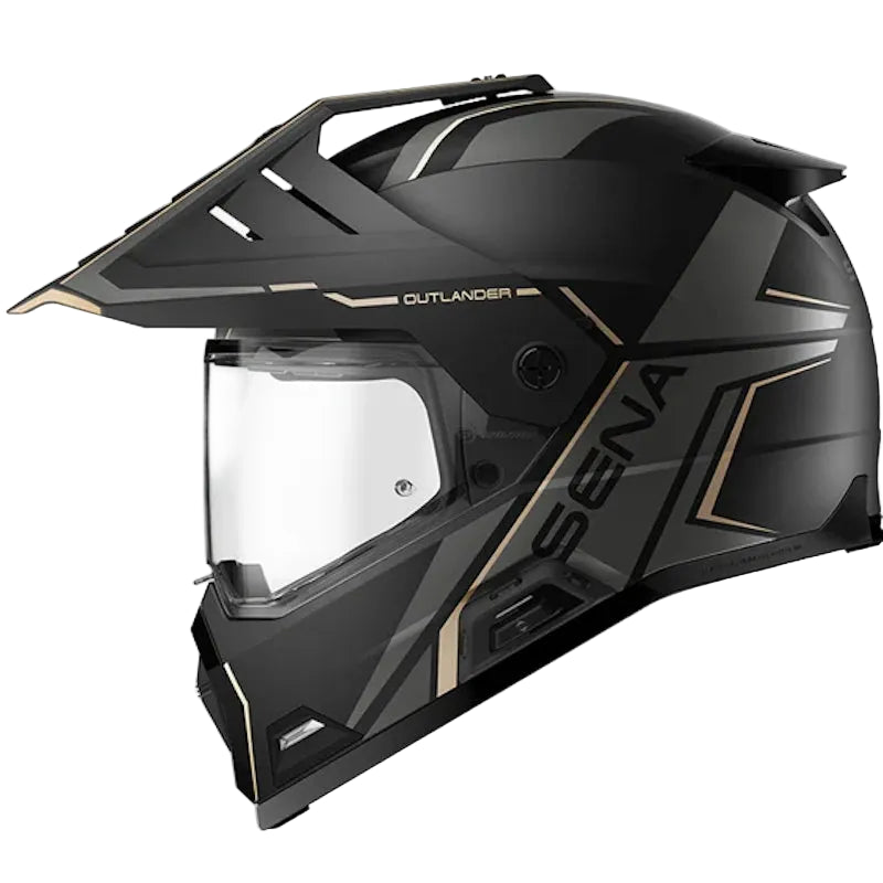 A black full-face off-road motorcycle helmet with gold accents and a clear visor, shown from a three-quarters angle on a light gray background. The brand 'SENA' is visible on the side.