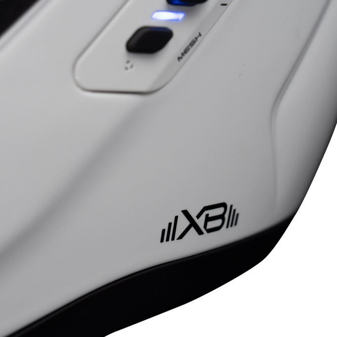 Close-up of a white electronic device with a black X3 logo, a black button, and a blue illuminated indicator, showing part of its control panel.