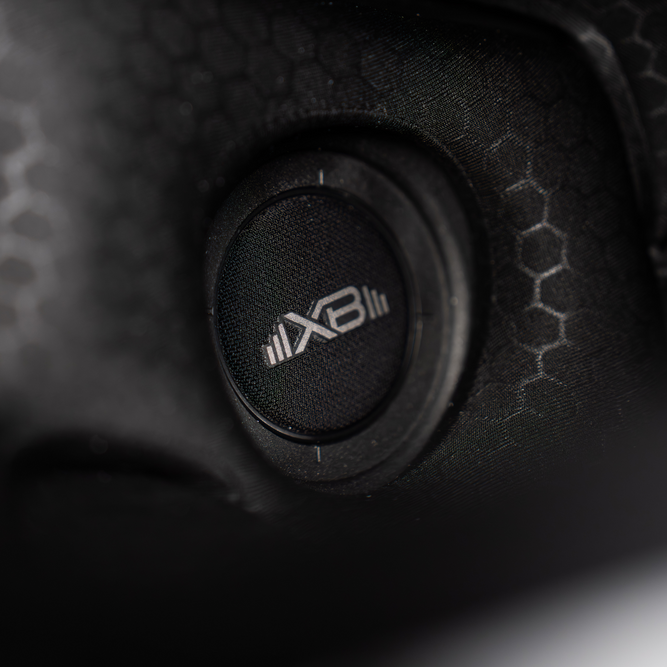 Close-up of a black speaker with 'XB' logo on a textured surface
