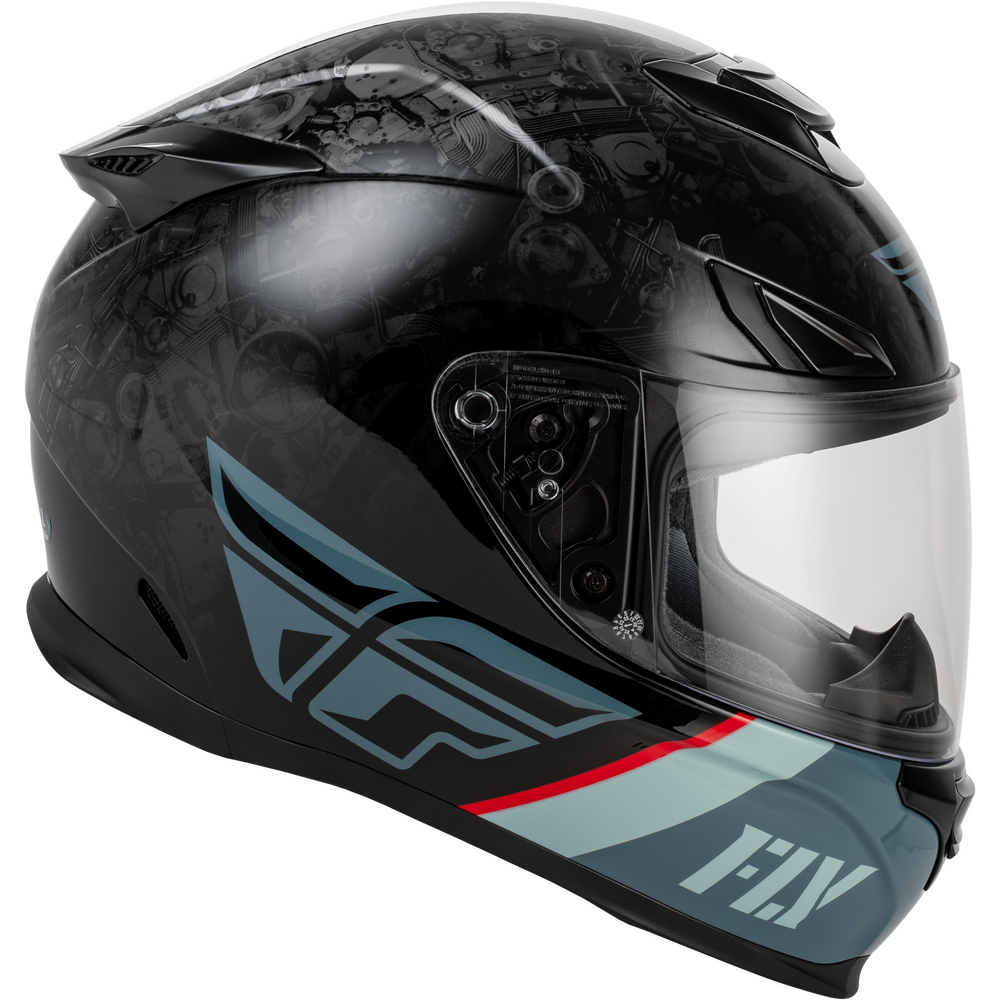 A Fly Racing full-face motorcycle helmet in black with a subtle skull graphic pattern, featuring light blue and red graphics on the lower side, and a clear visor.