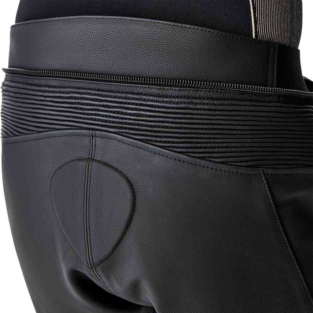 Close-up of black protective cycling shorts showing the rear panel with a padded seat cushion, a horizontal compression band, and a zipper closure.