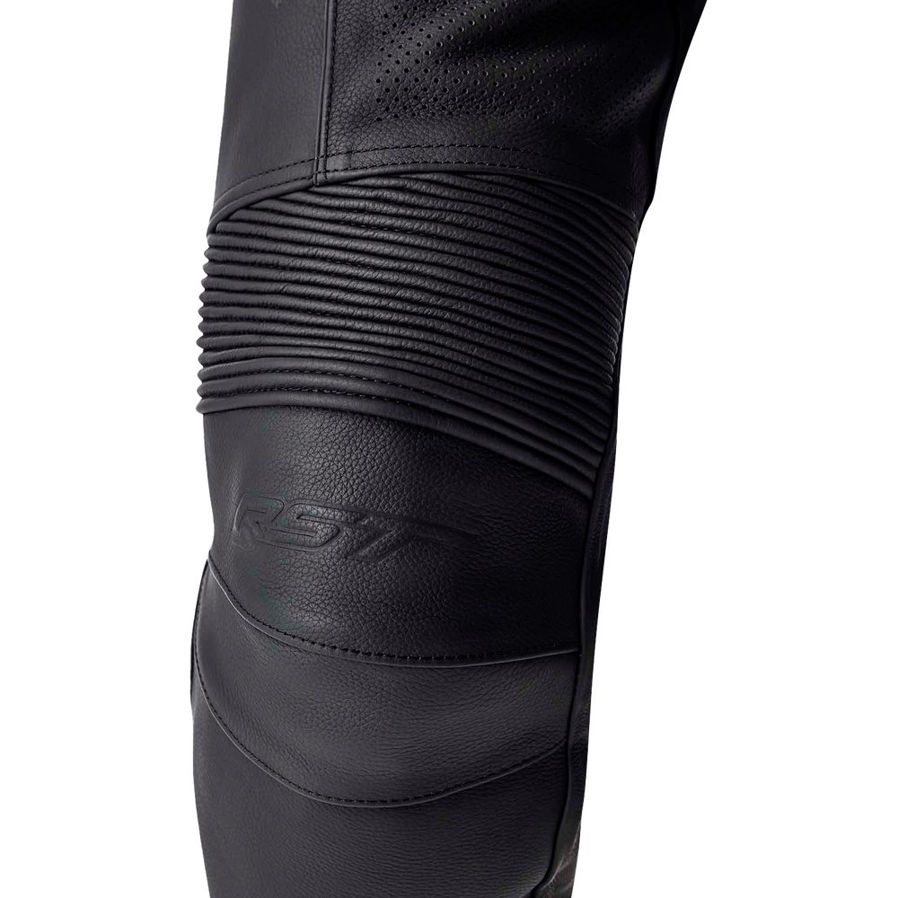 Close-up of a black motorcycle jacket leg panel with textured leather, perforated fabric, and horizontal ribbed compression sections, featuring an embossed SSV logo.