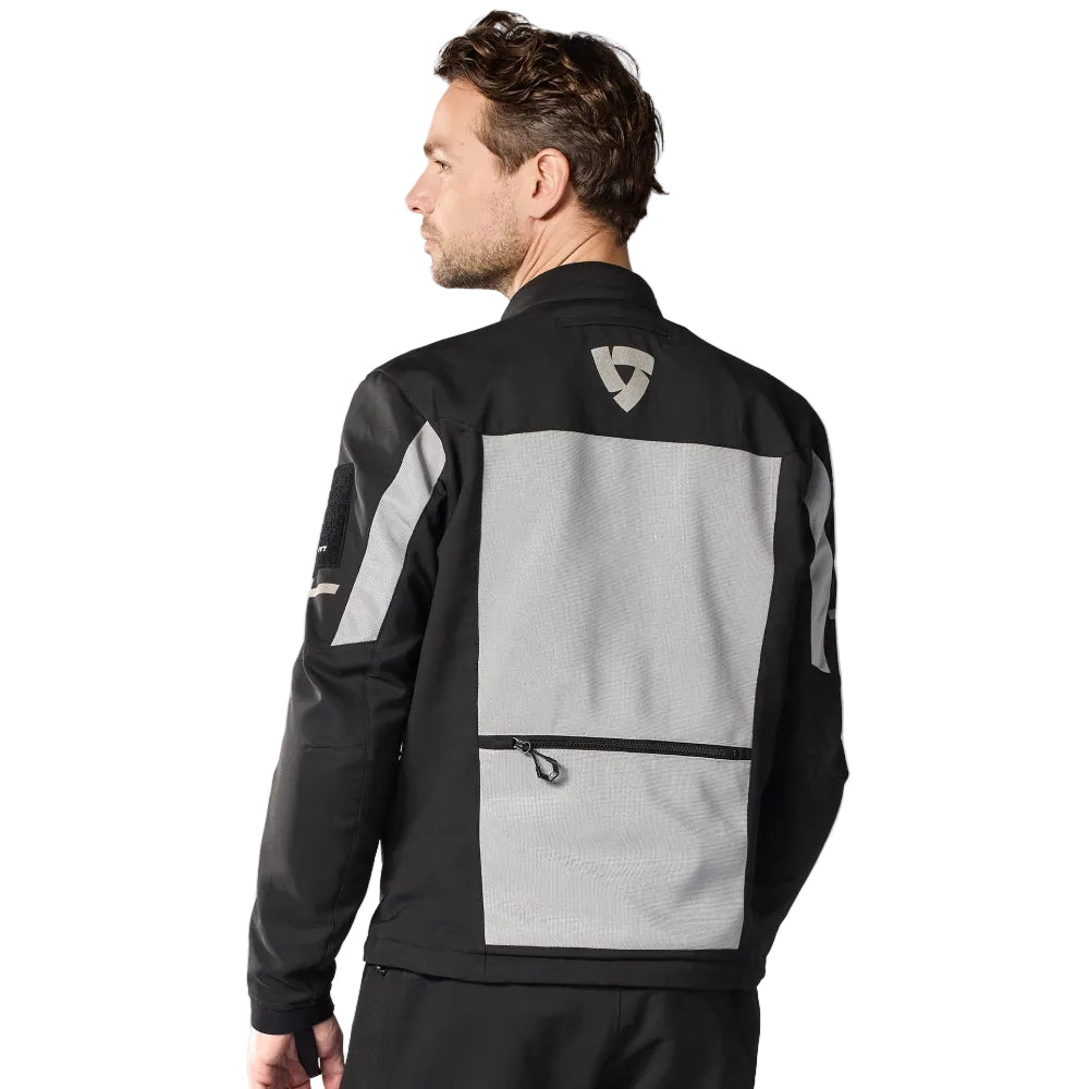 Person wearing a black and gray jacket with reflective elements on a white background