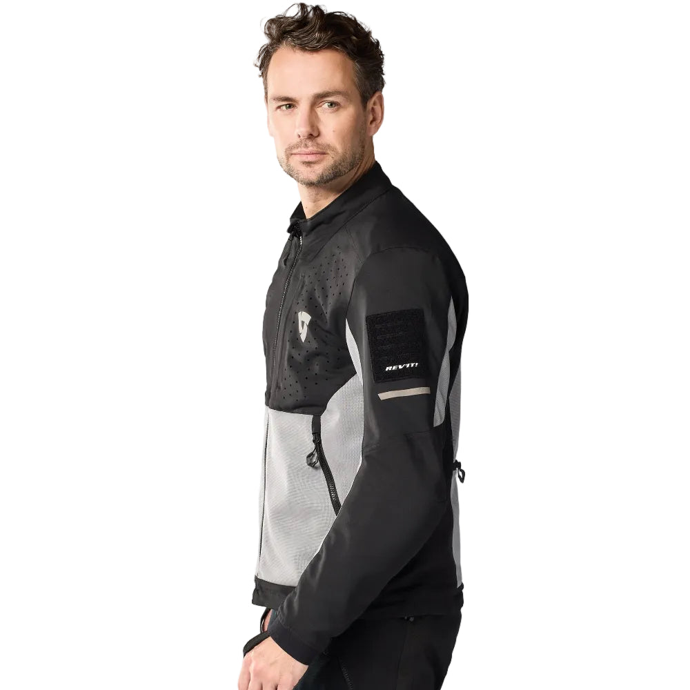 Man wearing a black and gray jacket with visible branding on a white background
