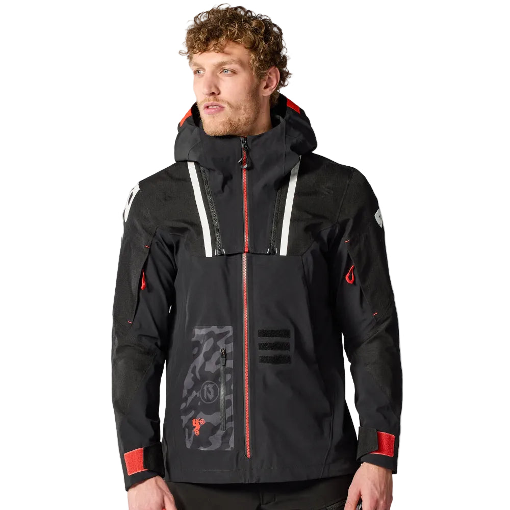 Man wearing a black and red jacket with visible branding on a white background