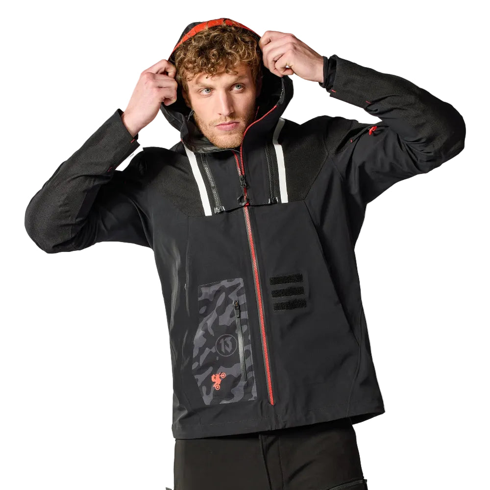 Person wearing a black and red jacket with a hood, standing against a white background