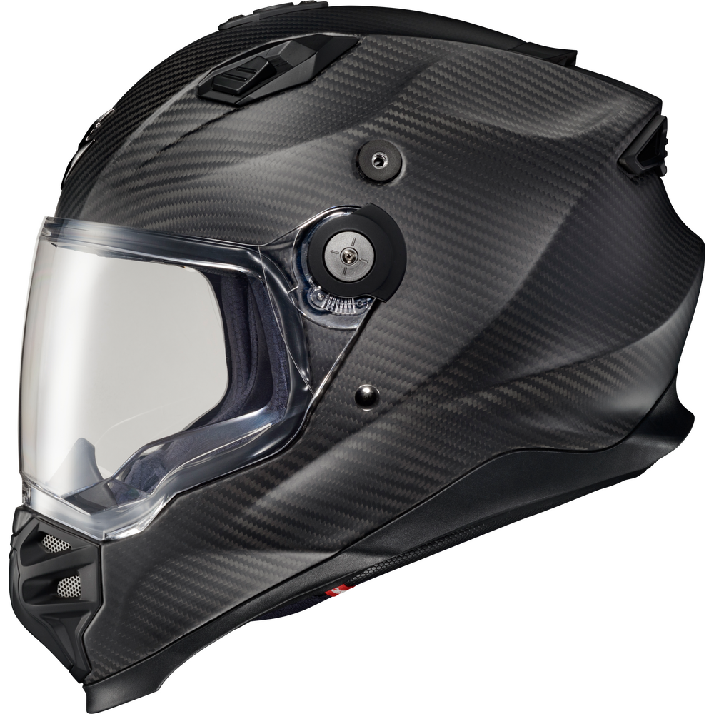 A full-face motorcycle helmet with a black carbon fiber pattern, featuring a clear visor and a black dial system on the side.