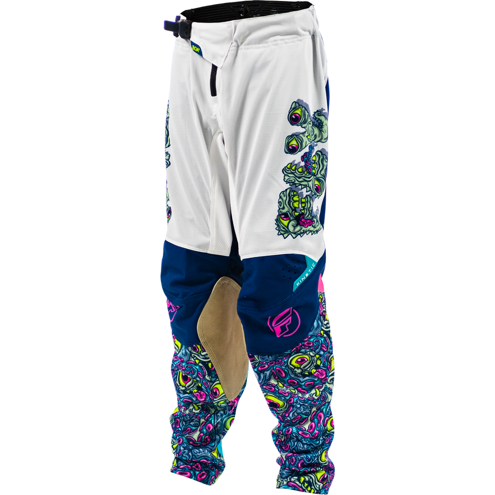 White motocross pants with navy blue knee panels, a beige abrasion patch, and vibrant multicolor psychedelic patterns on the lower legs and side.