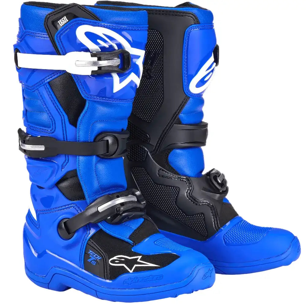 A pair of Alpinestars dirt bike boots in vibrant blue and black, featuring white logo details and white buckle accents, set against a plain white background.